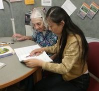 Photo of two adults reading an open notebook